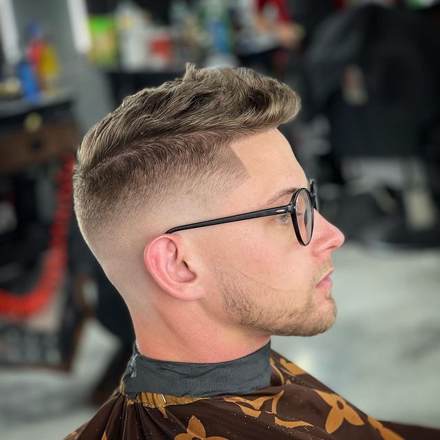 A man wearing glasses is getting his hair cut by a barber