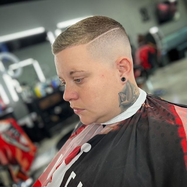 A man with a tattoo on his neck is getting his hair cut by a barber.