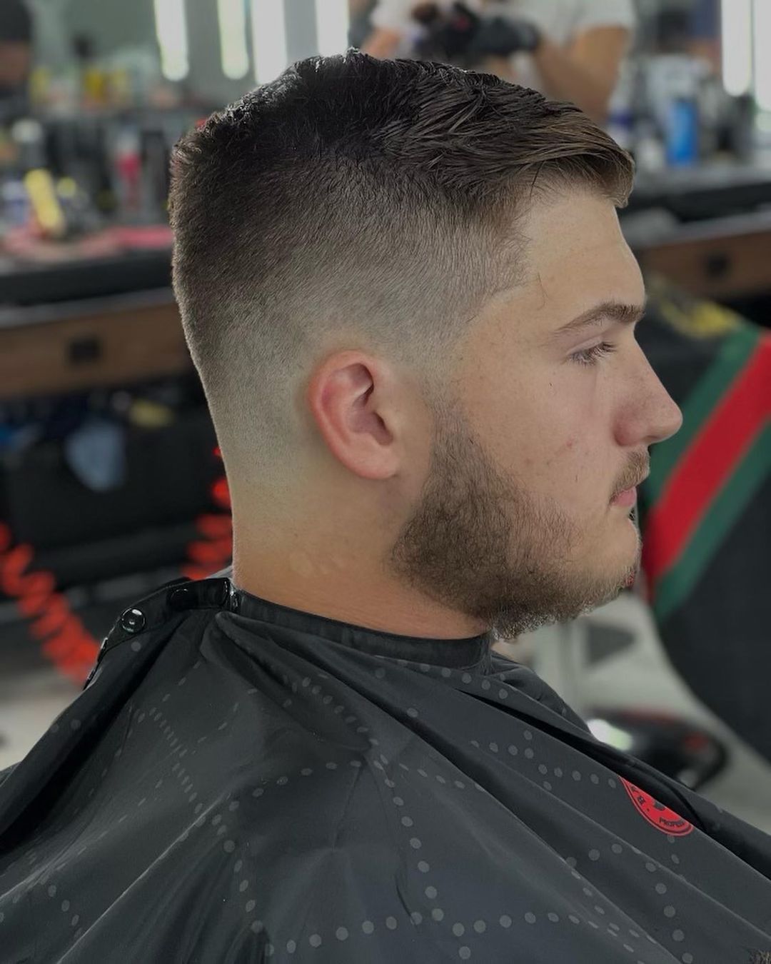 A man with a beard is getting his hair cut at a barber shop.