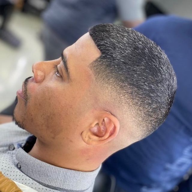 A man with a beard is getting his hair cut by a barber