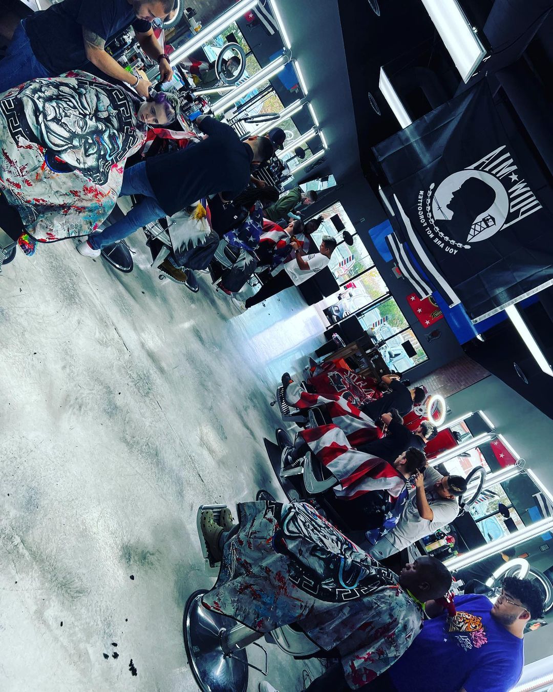 A group of people are getting their hair cut at a barber shop.