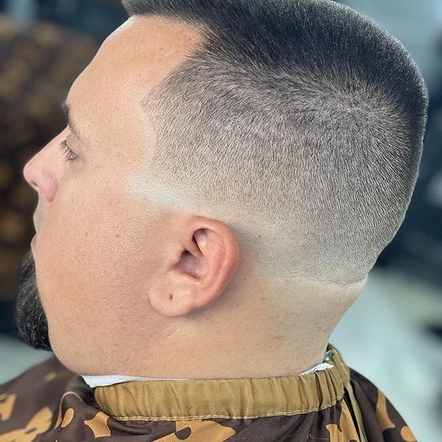 A man with a beard is getting his hair cut by a barber