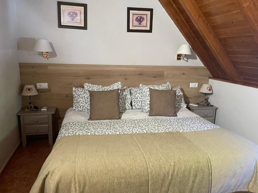 Un dormitorio con cama, mesitas de noche, lámparas y cabecero de madera.