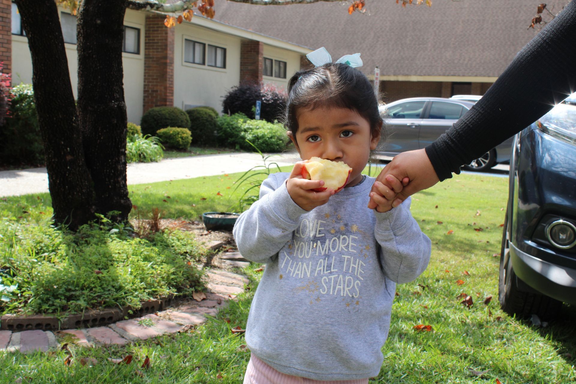 Young child smiling and eating an apple at a Food From the Heart event hosted by LCD.