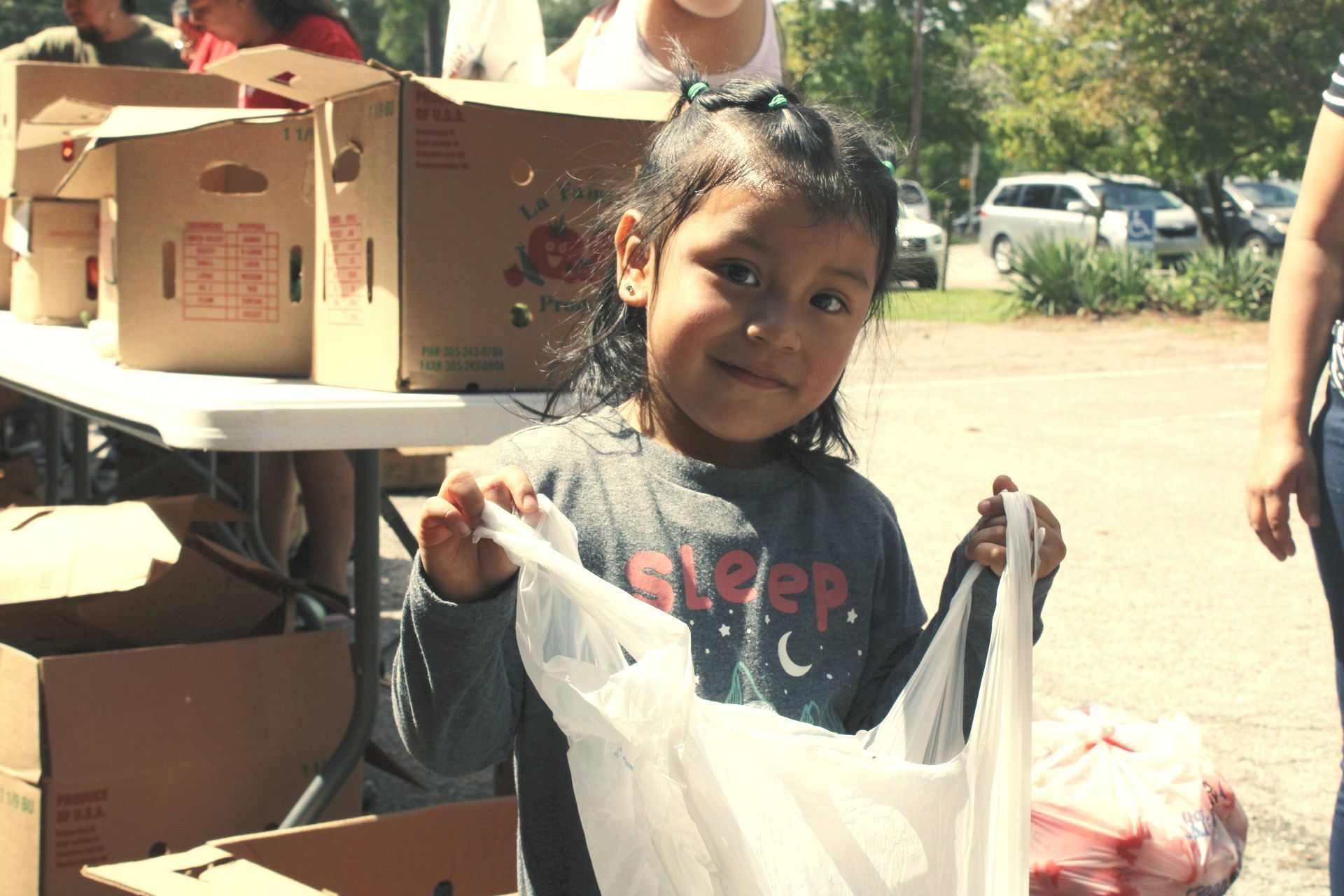 A young girl shows off her bag of fresh produce.