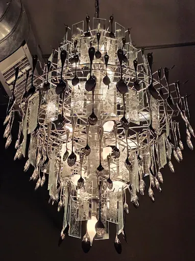 Chandelier made from spoons and glass, hanging from a ceiling.