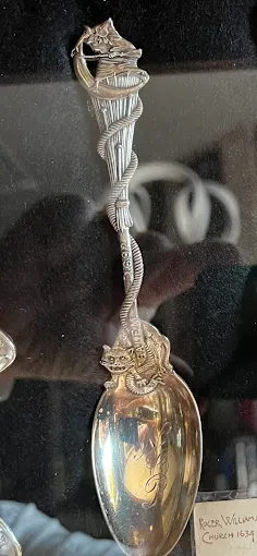 Silver spoon with ornate handle featuring a torch.