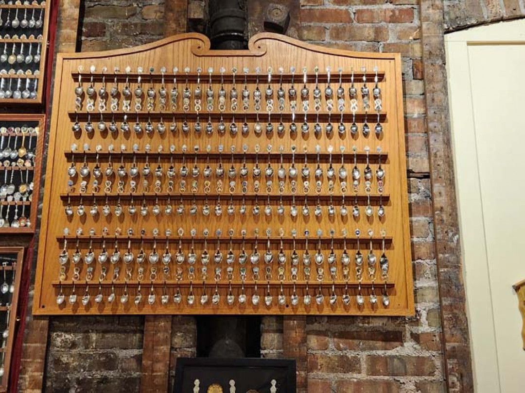 Wooden key rack on a brick wall, filled with numerous keys.