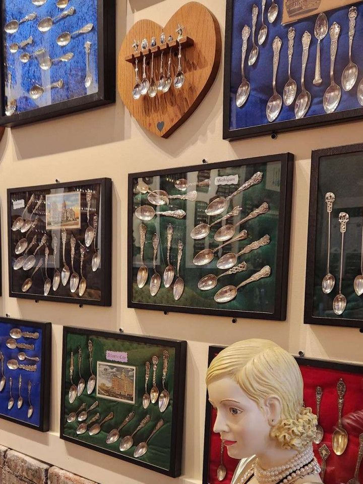 Display of antique spoons in framed cases and on a heart-shaped plaque.