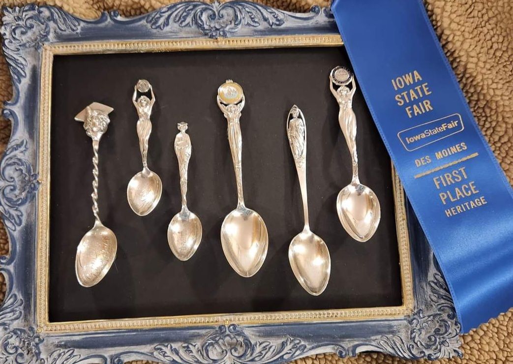Silver spoons displayed in a framed box.