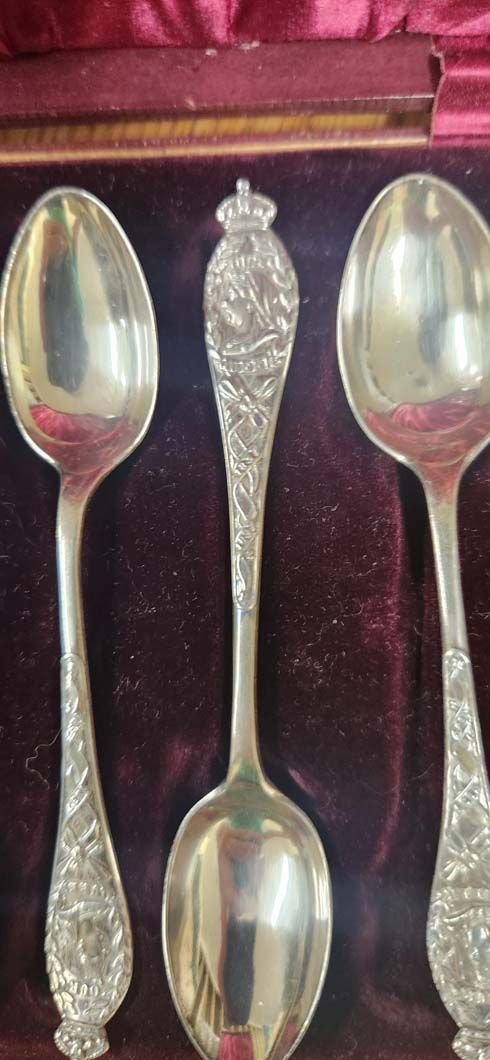 Three silver spoons in a velvet-lined box. 