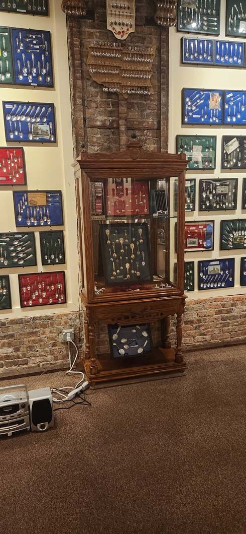 A wooden display cabinet with glass doors is in front of a wall with framed items.