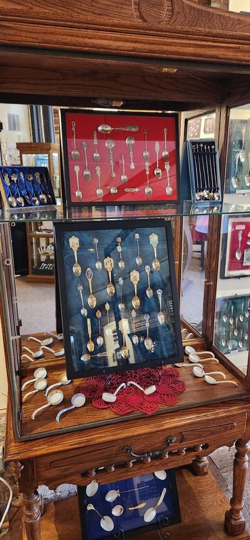 Wooden display cabinet with framed keys, spoons, and a red display case.