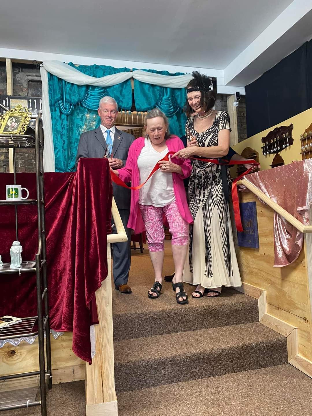 People cutting a red ribbon on stairs, likely at an opening ceremony.