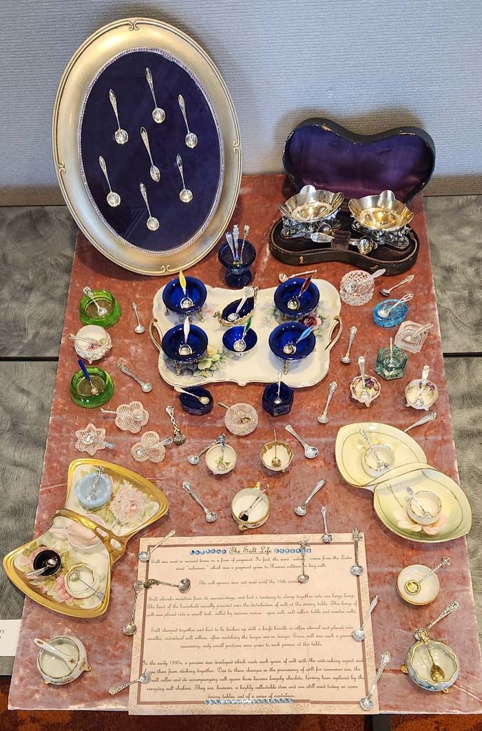 A collection of ornate dishware, including spoons, bowls, and serving dishes, on a wooden surface.