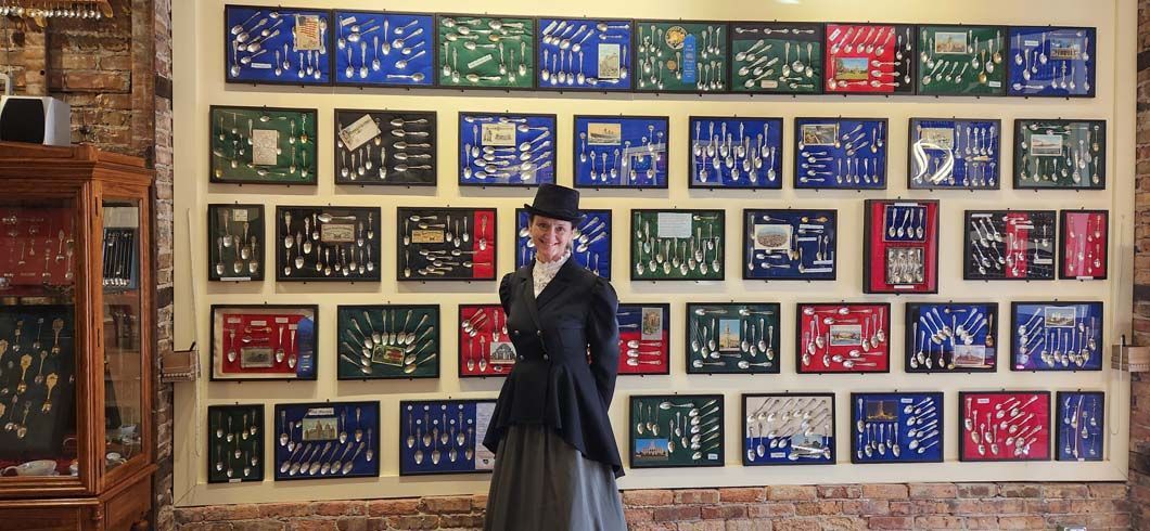 Woman in vintage outfit stands before a wall of framed circuit boards, inside a room.