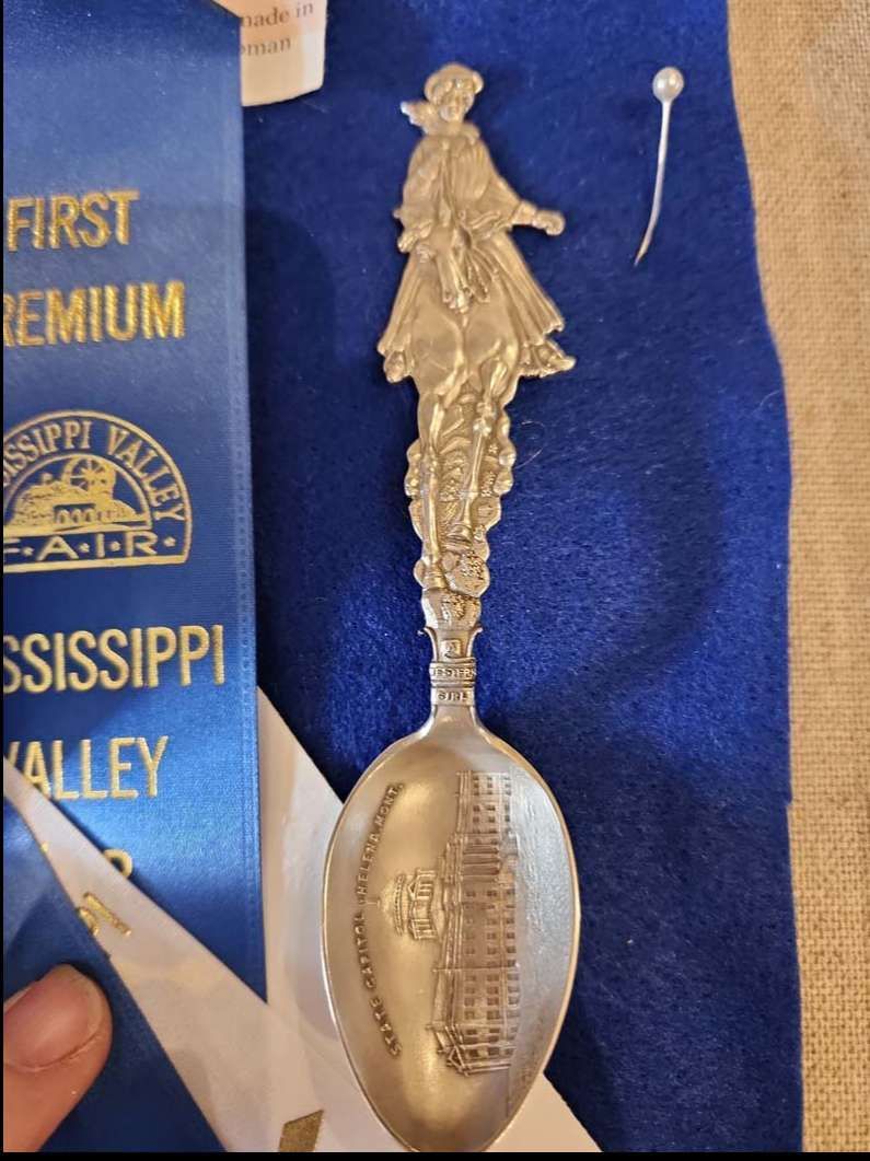 Blue ribbon next to an ornate silver spoon.