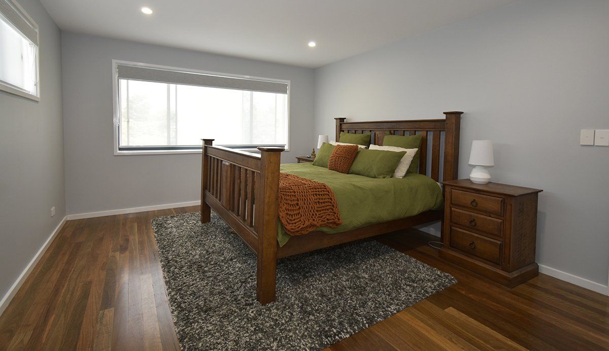 A bedroom with a bed, nightstand, rug and window.
