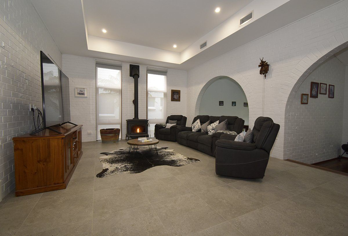 A living room with a couch, chairs, a television and a fireplace.