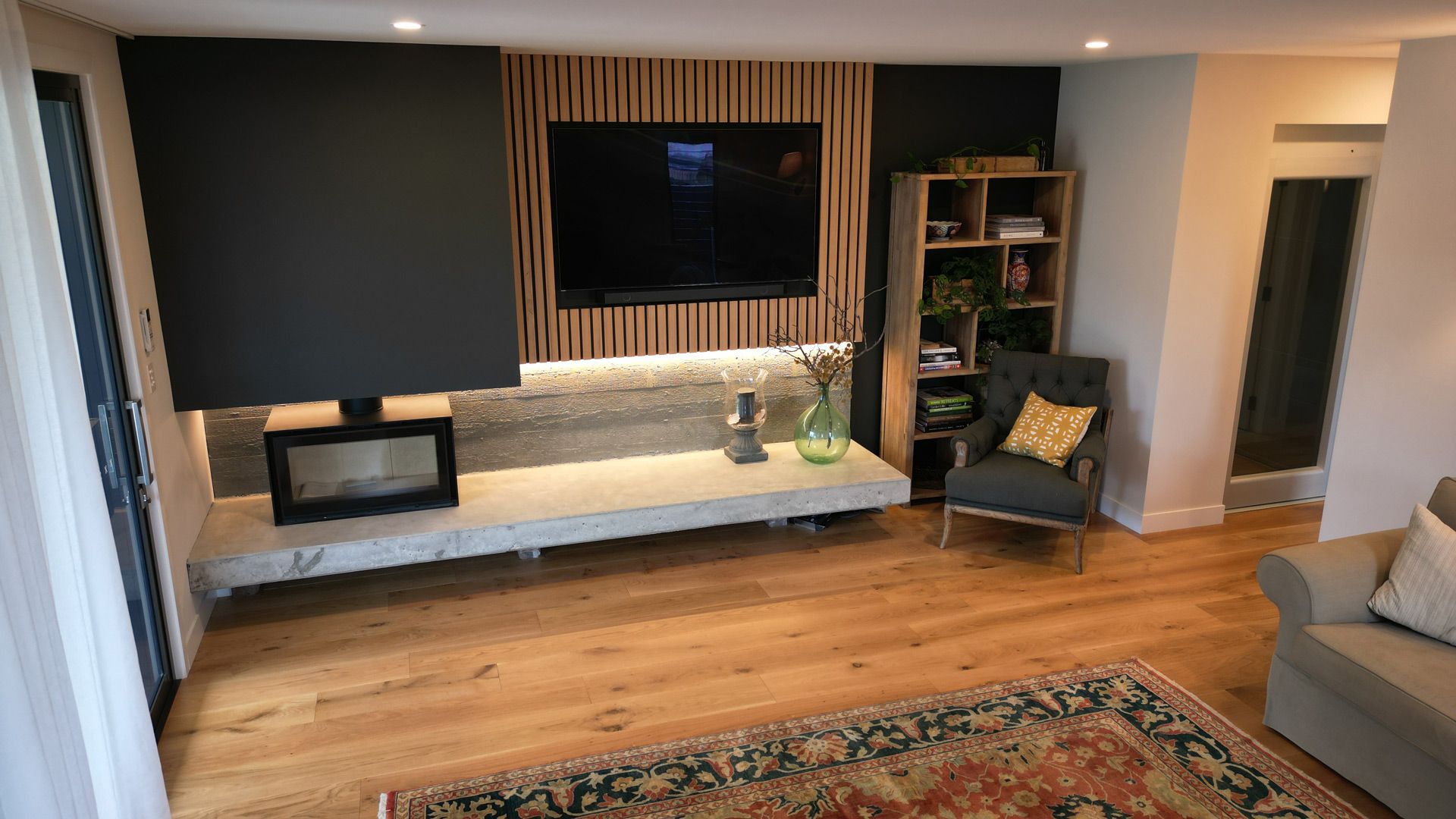 A living room with a fireplace, television, chair and rug.