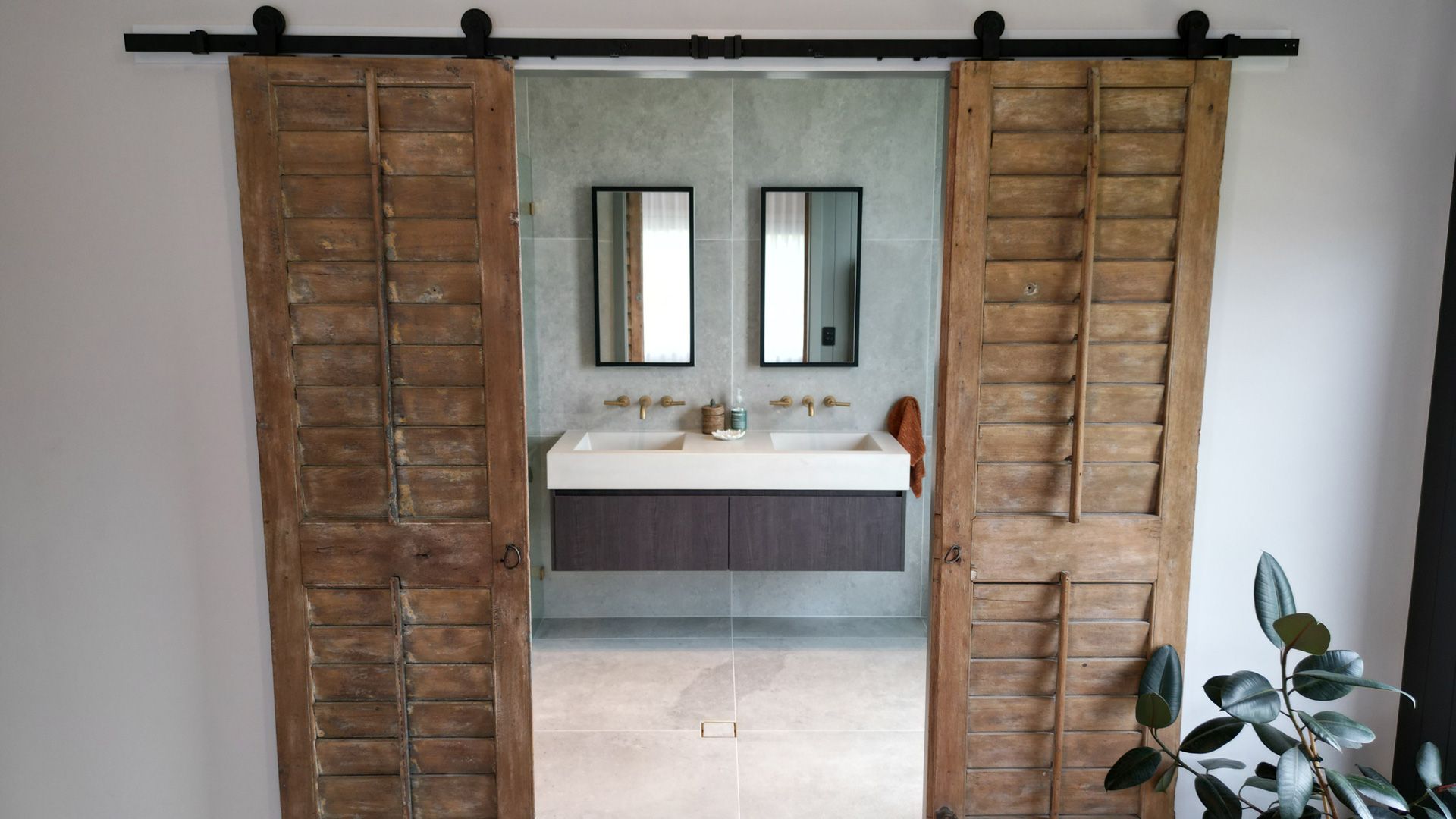 A bathroom with two sinks and two mirrors behind sliding barn doors.