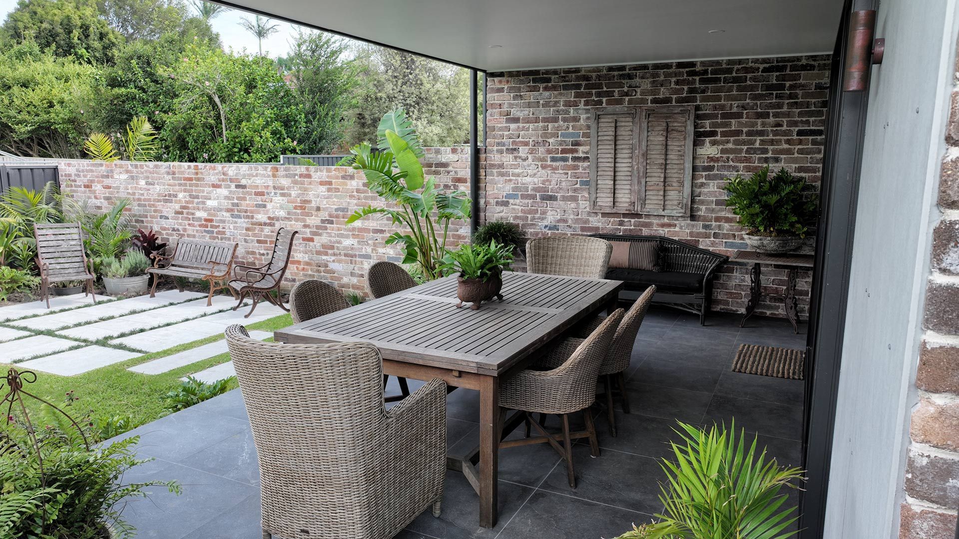 A patio with a table and chairs in front of a brick wall.