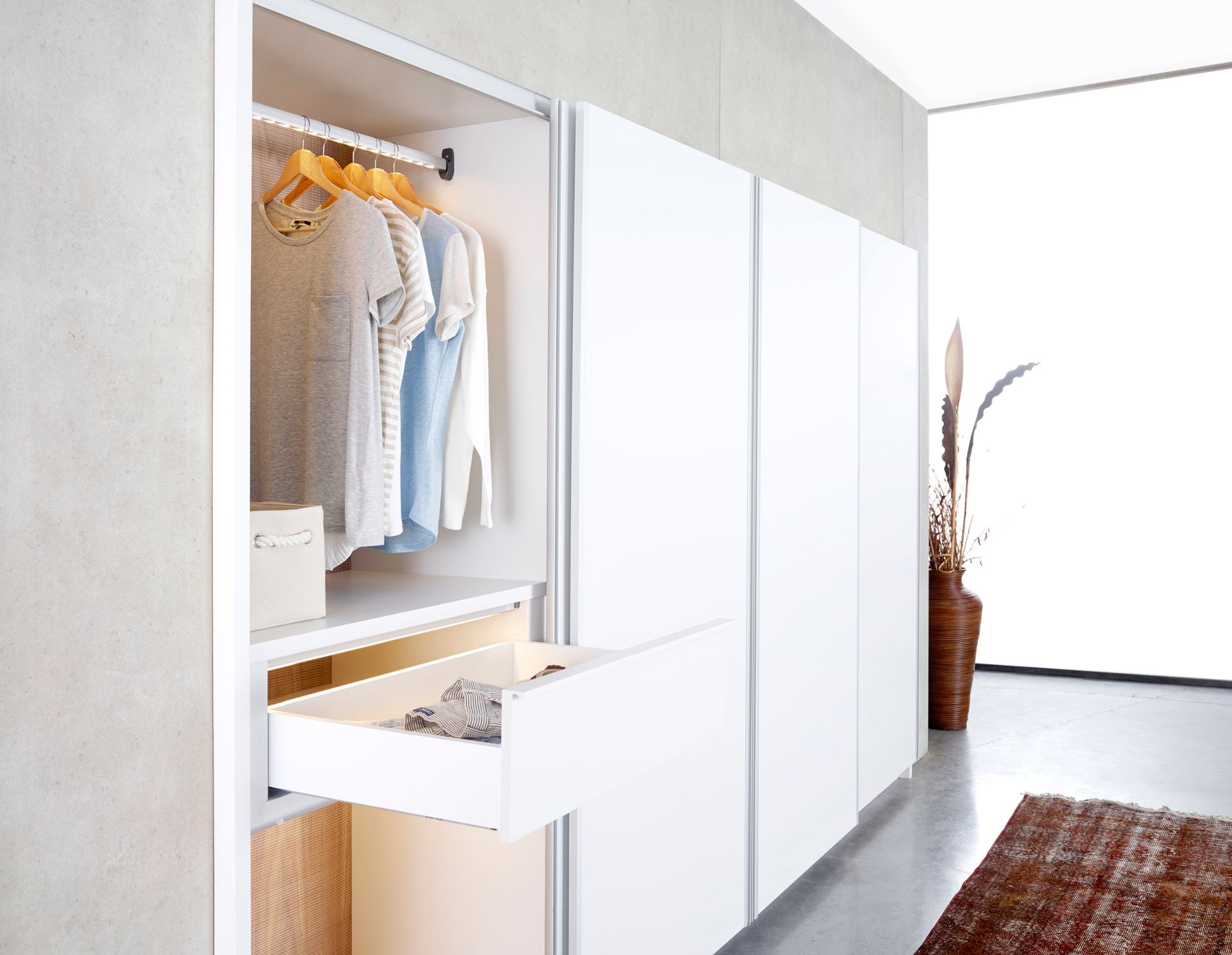 A closet with clothes hanging and a drawer open