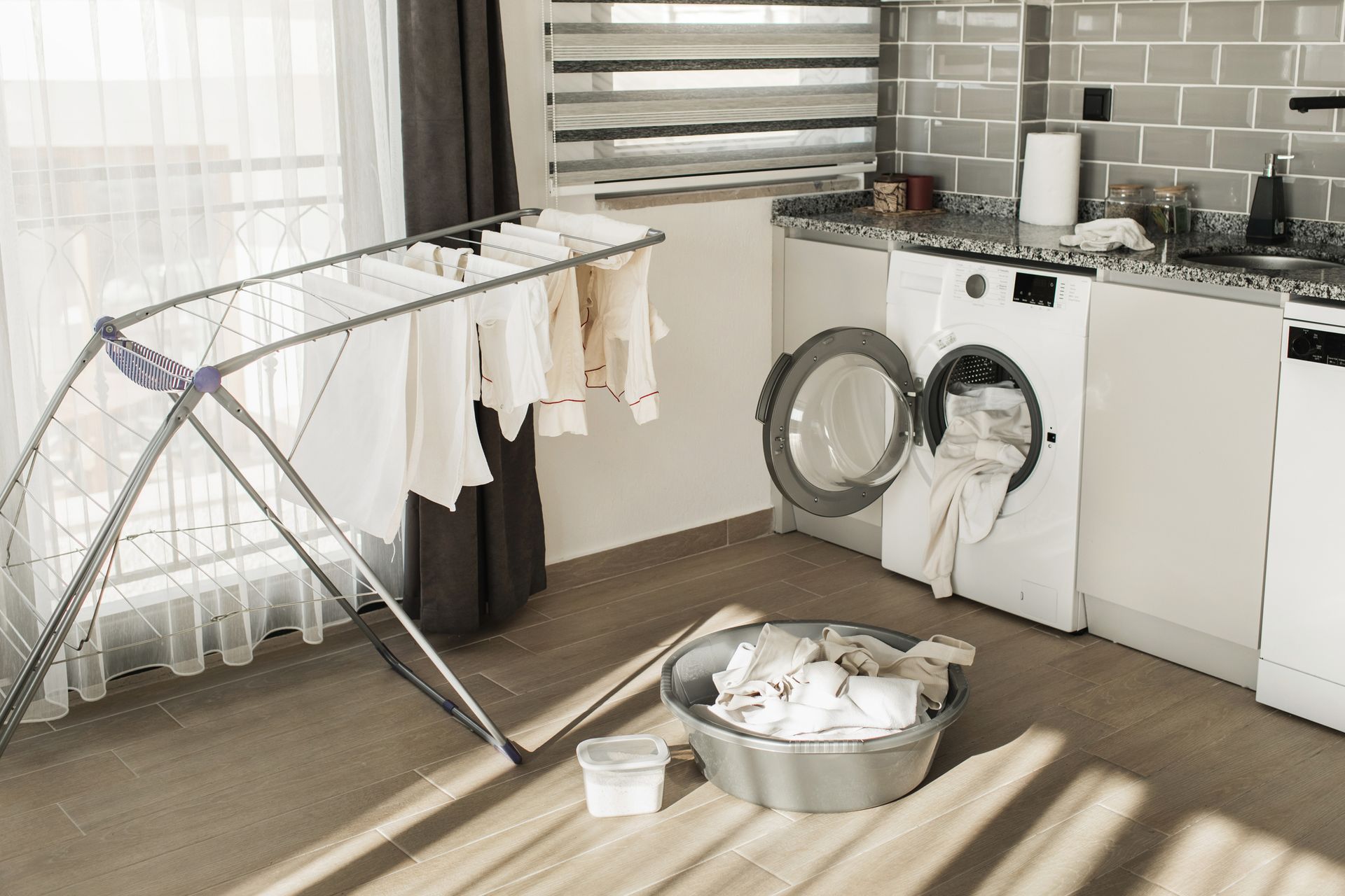 A kitchen with a washing machine and drying rack.