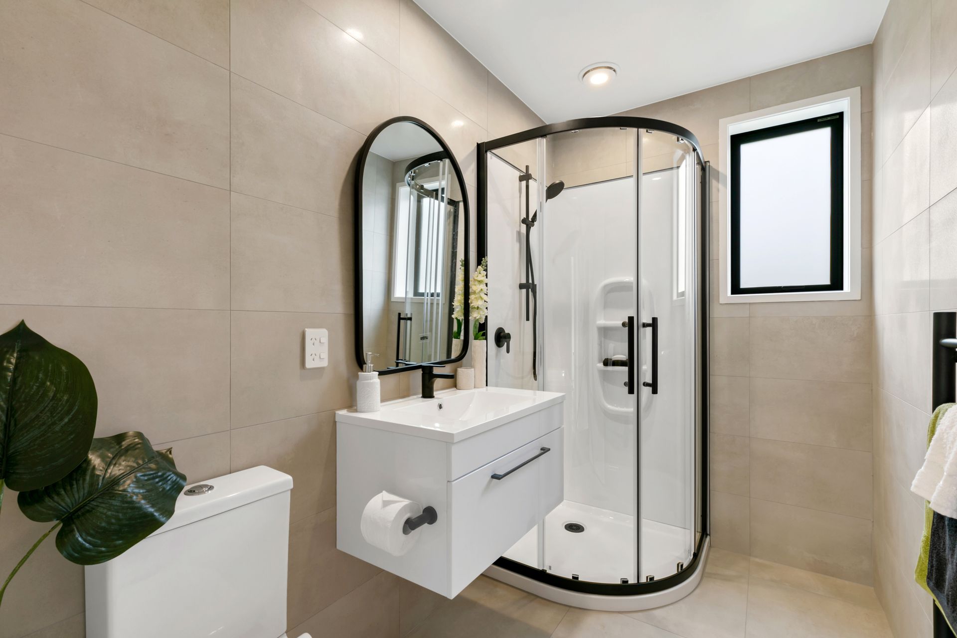 A bathroom with a toilet , sink , shower and mirror.
