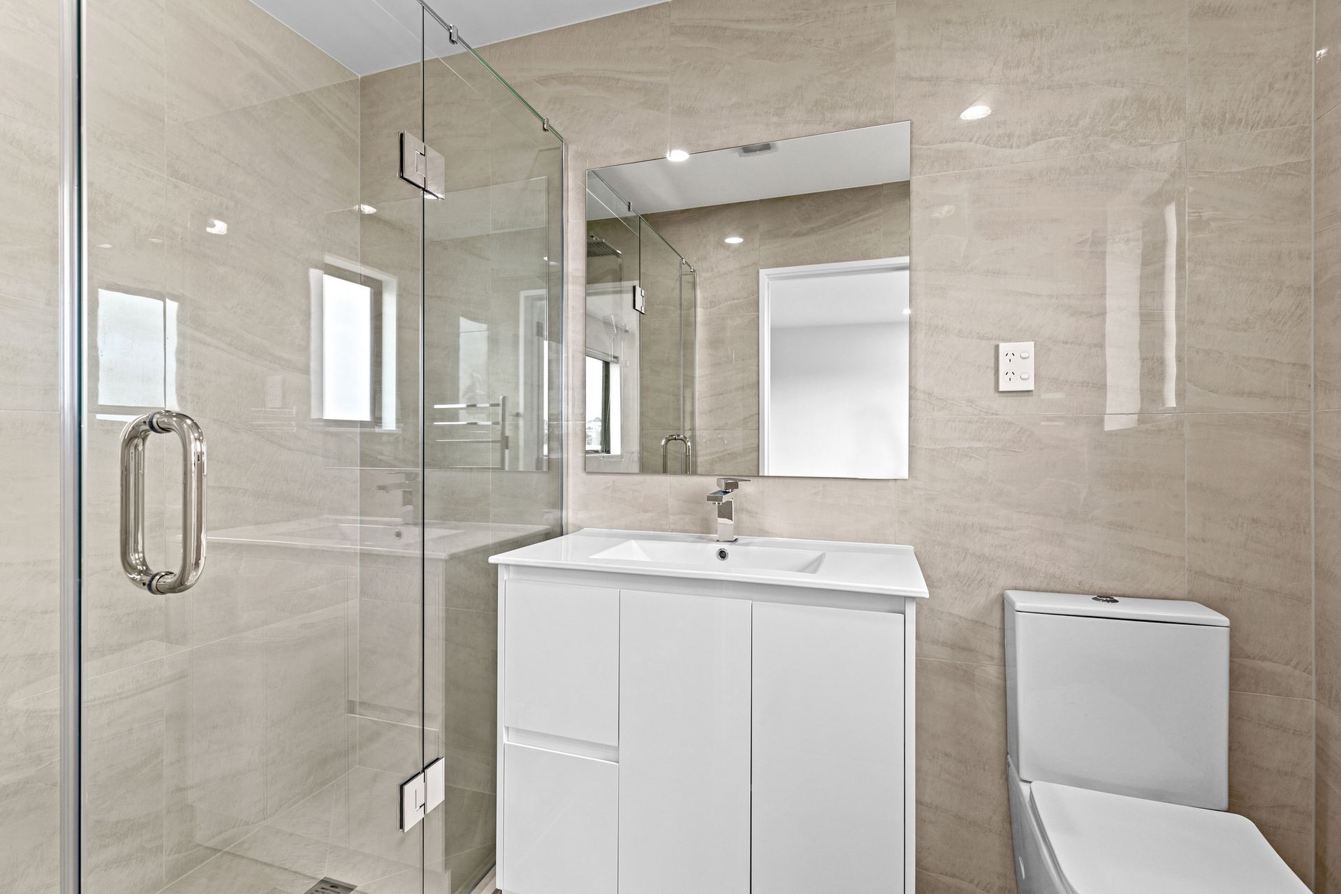 A bathroom with a sink , toilet , shower and mirror.