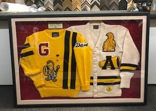 Two sweaters are framed in a glass case.