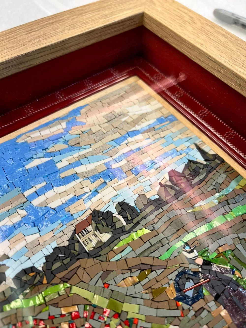 A close up of a mosaic painting in a wooden frame.