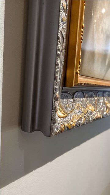 A picture frame is hanging on a white wall.