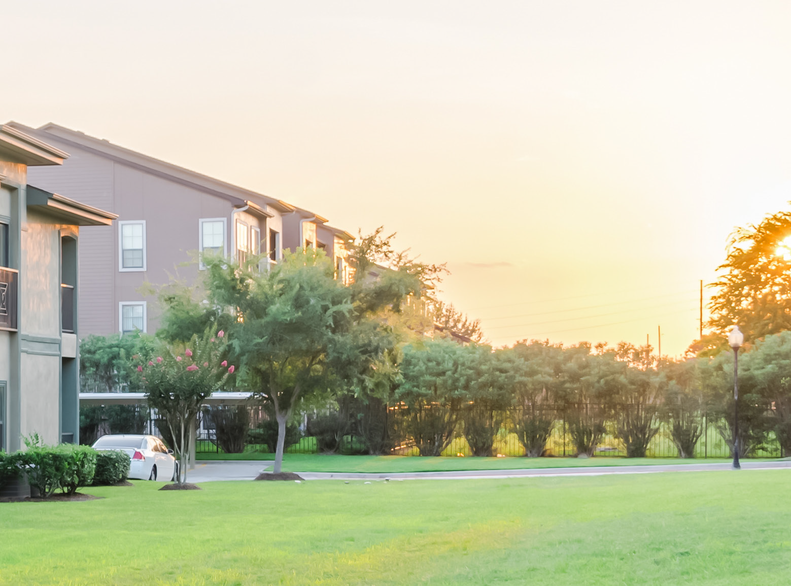 A large apartment building with a lush green lawn in front of it.