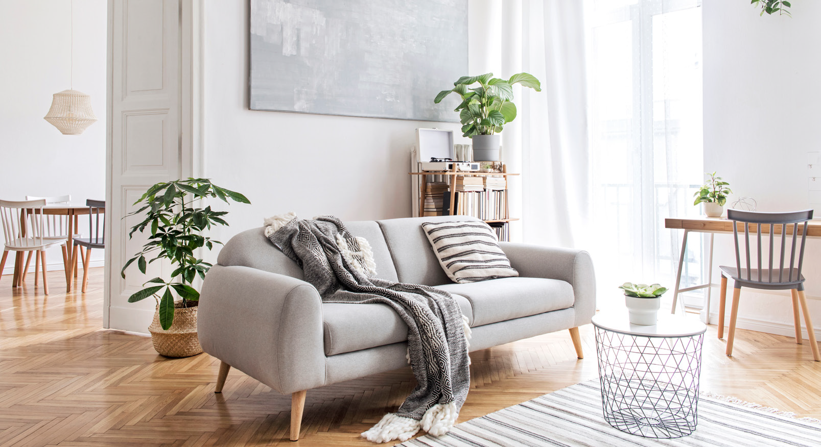 A living room with a couch , table , chairs and plants.