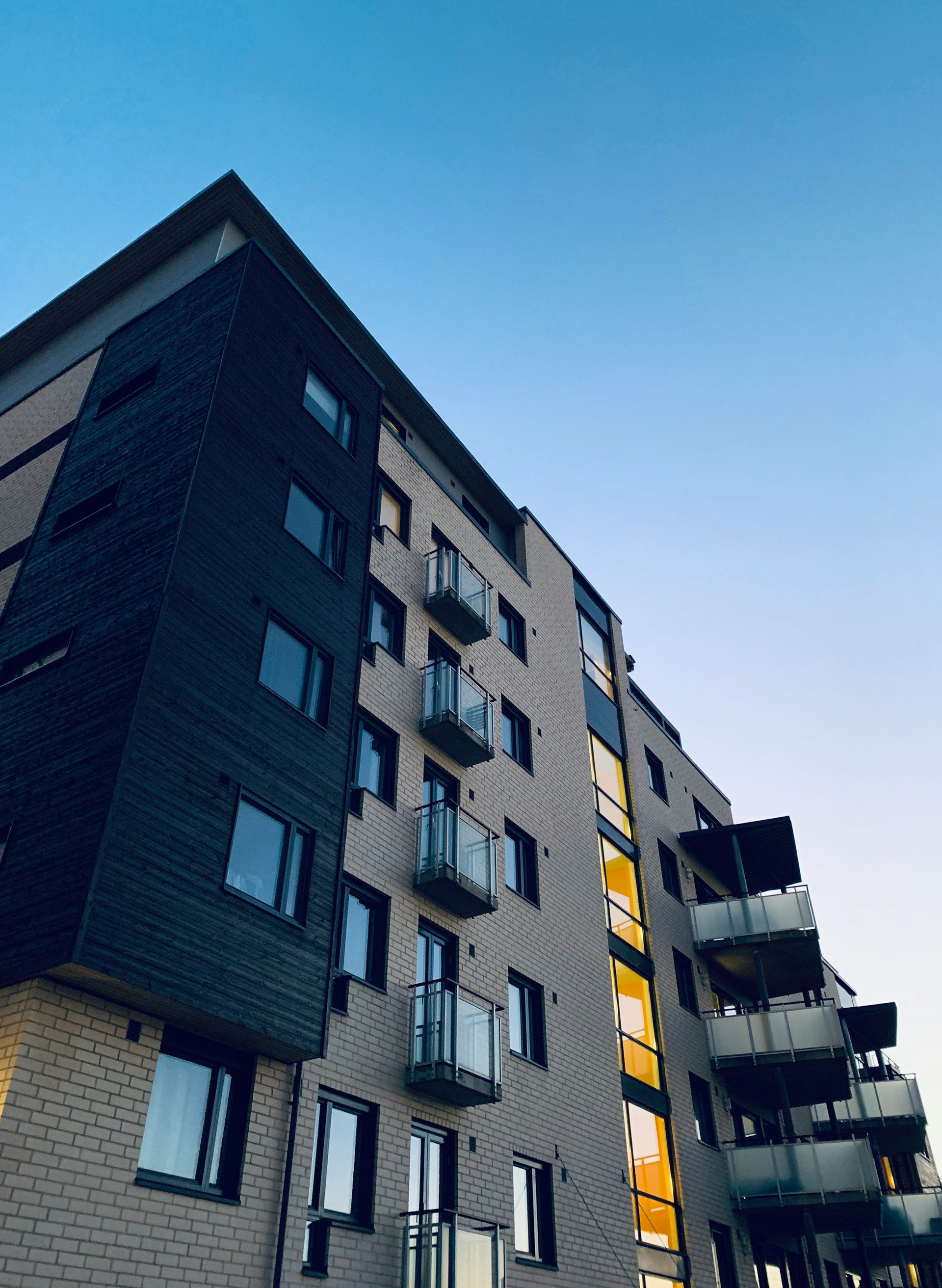 Looking up at a tall apartment building with balconies against a blue sky