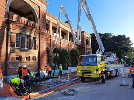 A group of construction workers are working on a sidewalk in front of a building.
