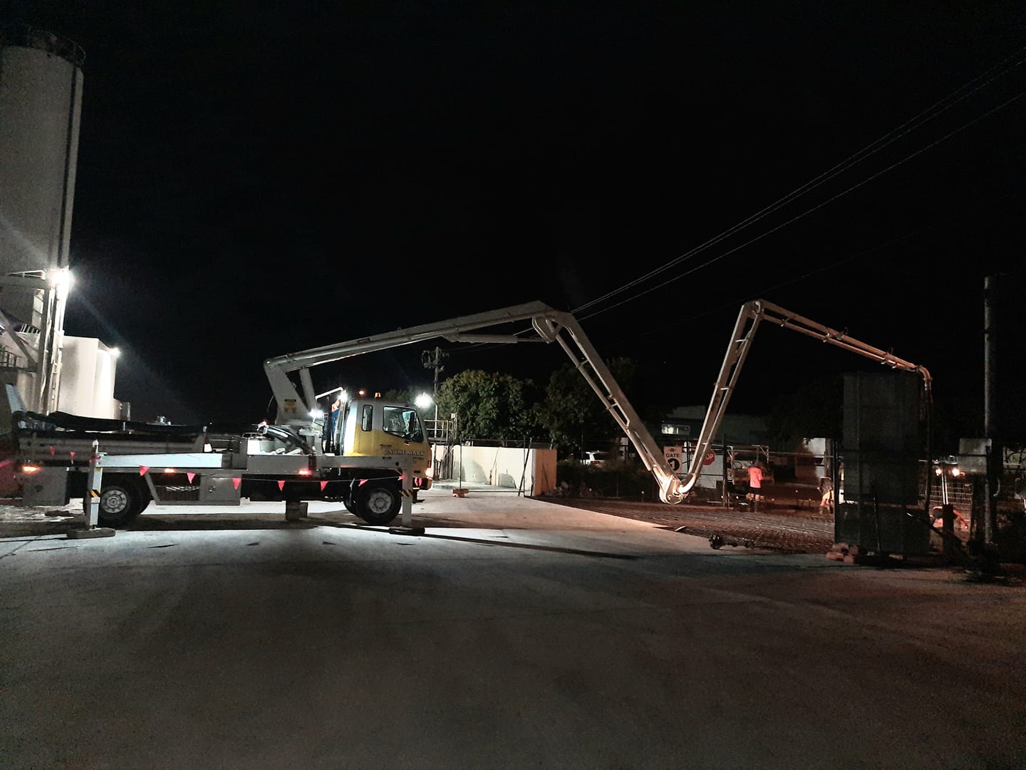 A concrete pump is pumping concrete into a truck at night.