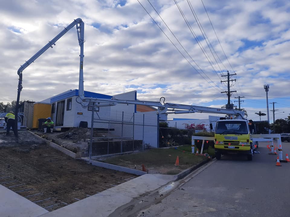 A yellow truck is parked in front of a building under construction.