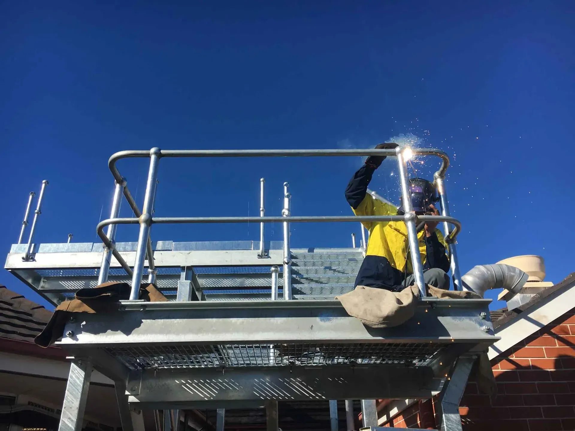 A Man Is Welding On Top Of A Metal Structure — BM Steel Fabrication In Forster, NSW