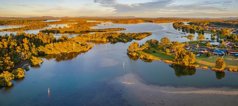 An Aerial View Of A Large Lake Surrounded By Trees And Houses — BM Steel Fabrication In Forster, NSW