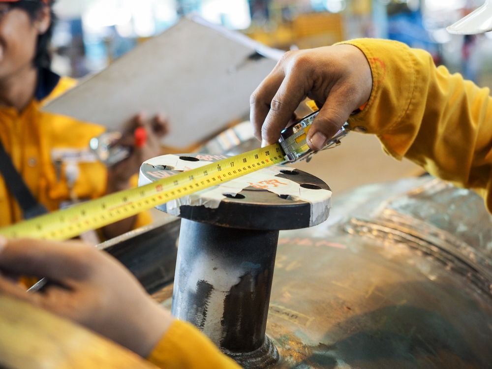 A Person Is Measuring A Pipe With A Tape Measure — BM Steel Fabrication In Pacific Palms, NSW