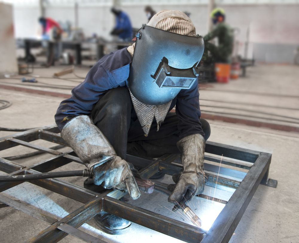 A Man Wearing A Welding Mask Is Welding A Piece Of Metal — BM Steel Fabrication In Pacific Palms, NSW