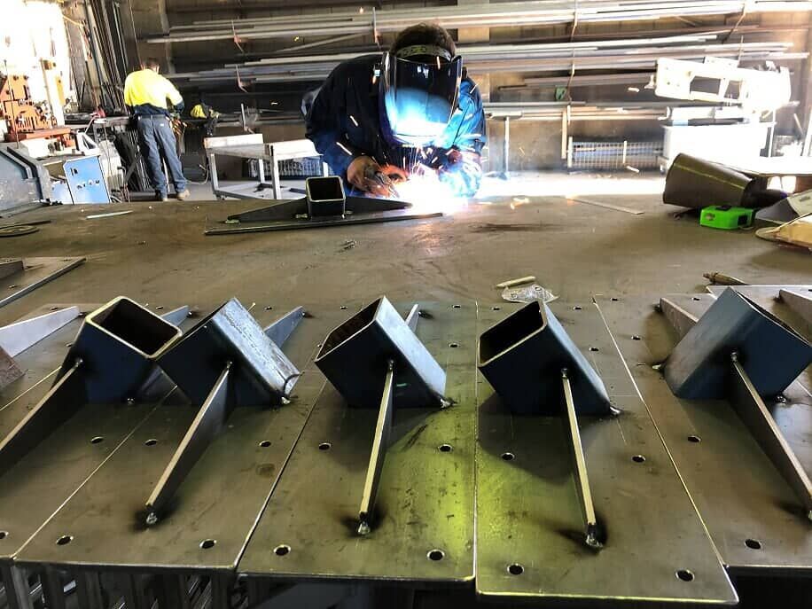 A Man Is Welding A Piece Of Metal In A Factory — BM Steel Fabrication In Forster, NSW