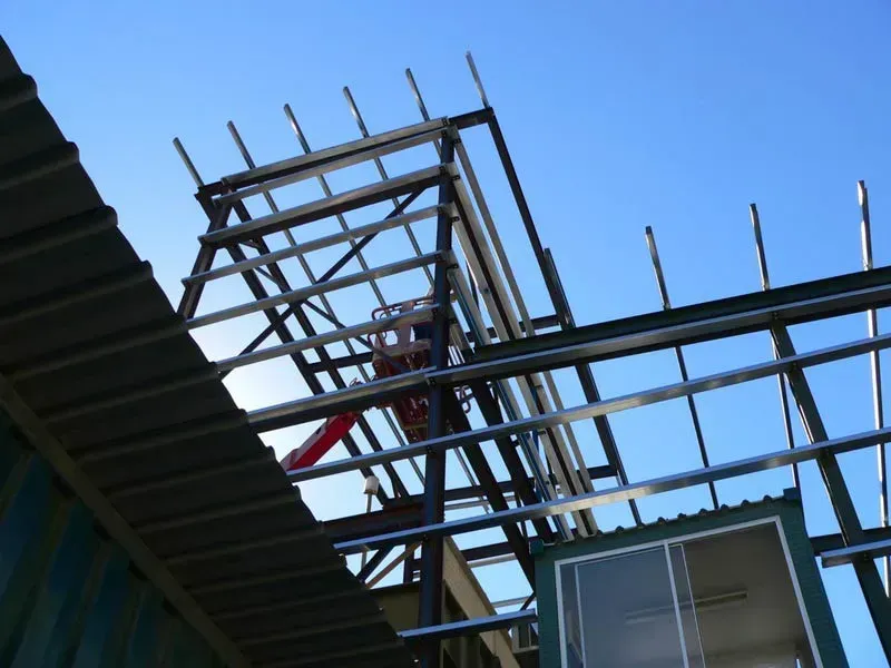 A Man Is Standing On A Ladder On Top Of A Metal Structure — BM Steel Fabrication In Forster, NSW
