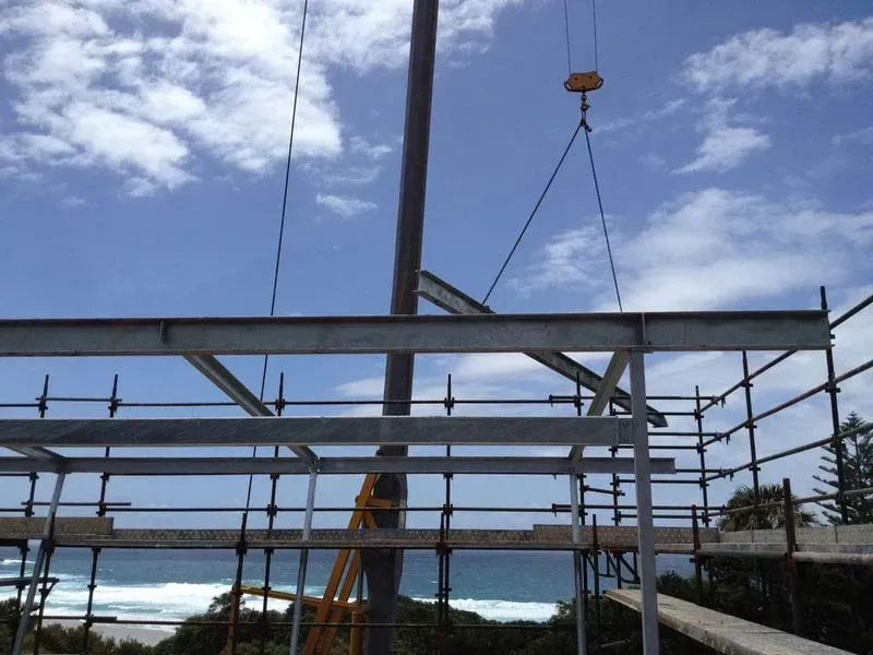 A Crane Is Lifting A Metal Structure Over A Beach — BM Steel Fabrication In Forster, NSW
