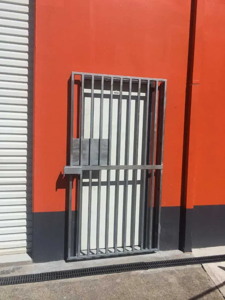 A Red Building With A White Door And A Metal Gate — BM Steel Fabrication In Forster, NSW