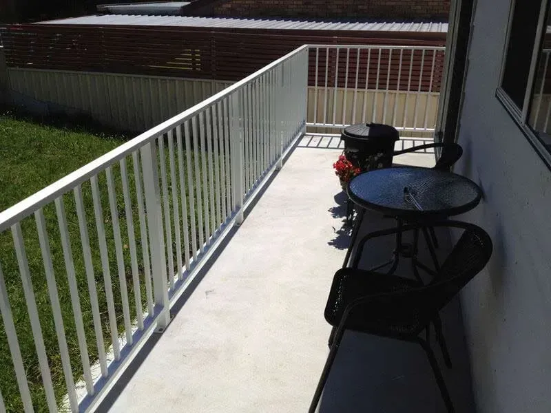 A Balcony With A Table And Chairs And A White Railing — BM Steel Fabrication In Forster, NSW