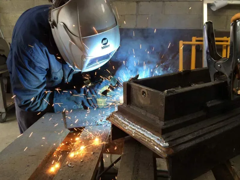A Man Wearing A Welding Helmet Is Welding A Piece Of Metal — BM Steel Fabrication In Forster, NSW