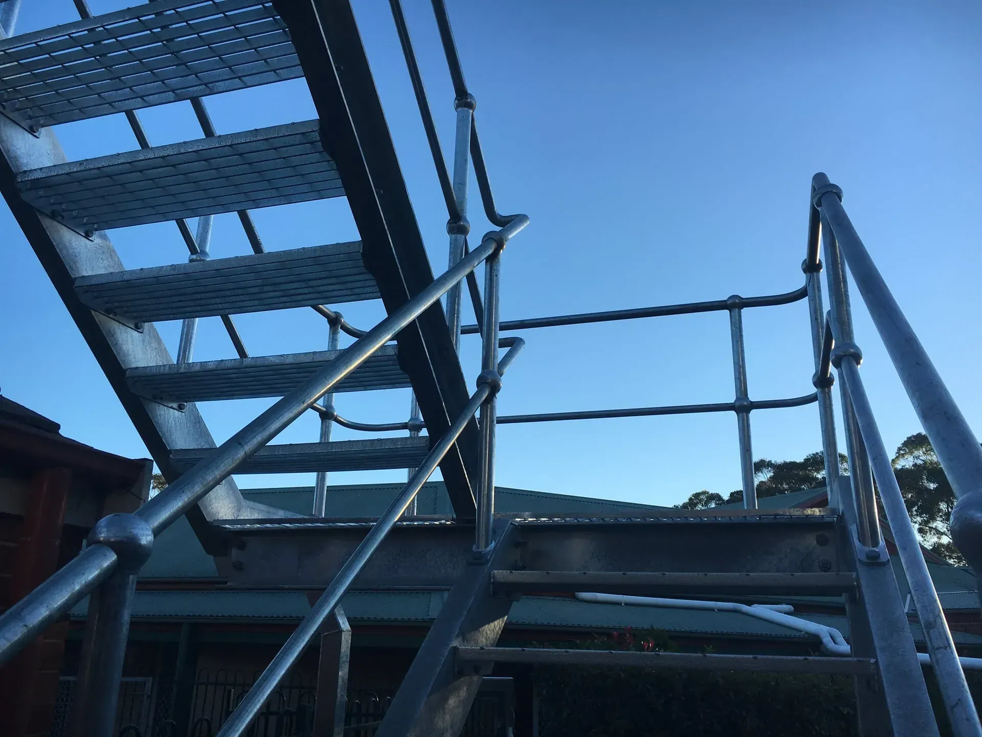 A Metal Staircase With A Railing And A Blue Sky In The Background — BM Steel Fabrication In Forster, NSW